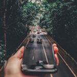 Forced Perspective Photography of Cars Running on Road Below Smartphone